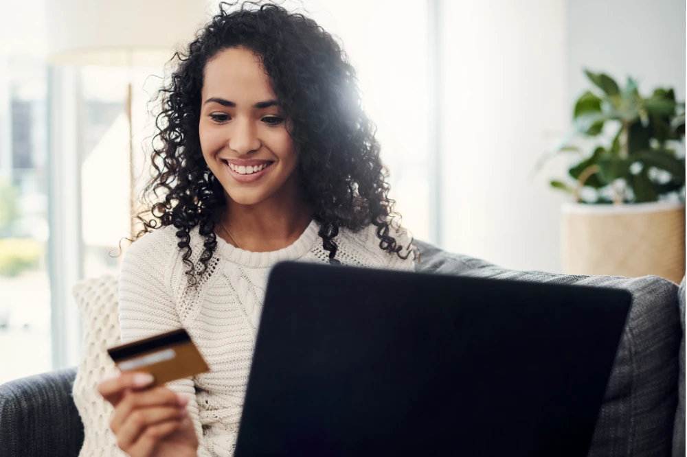 Smiling woman shopping online with a credit card and laptop